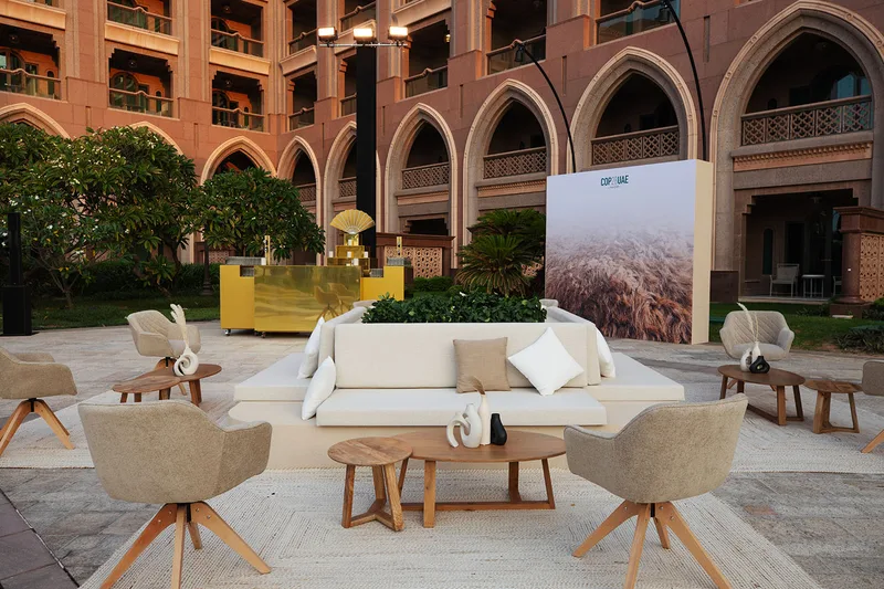 Beige sofas, accent chairs and layered rugs defining an elegant temporary hospitality lounge.